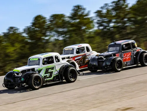 Three Legends cars racing side by side at Cordele Motor Speedway